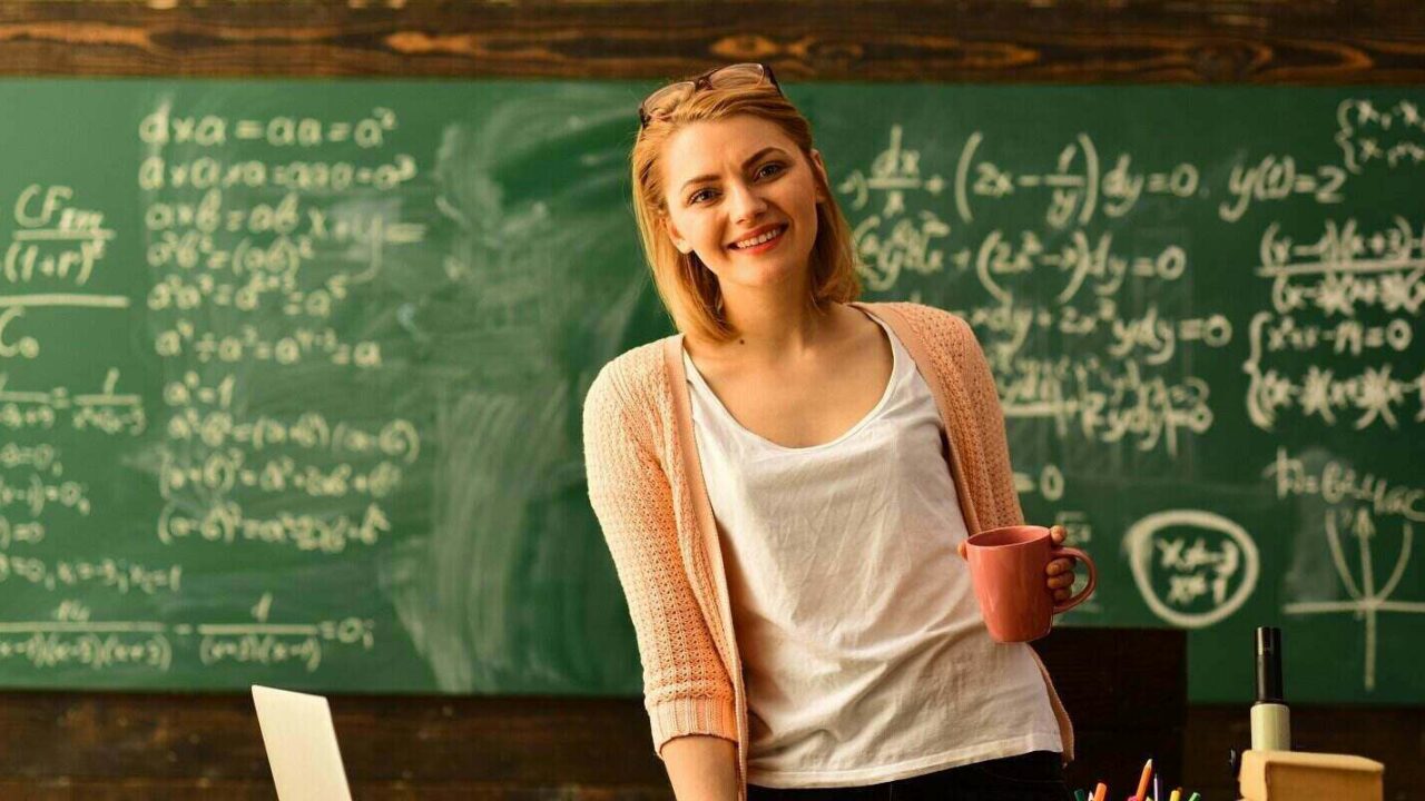 teacher holding cup in classroom