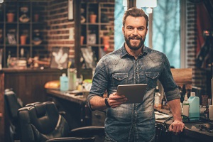 young bearded man looking at camera and holding digital tablet