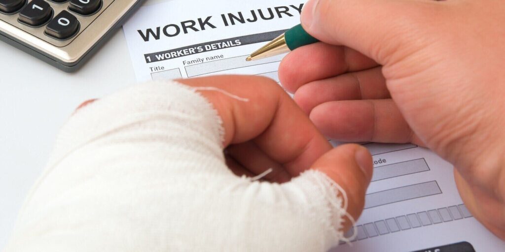 filling up a work injury claim form with a wrapped hand