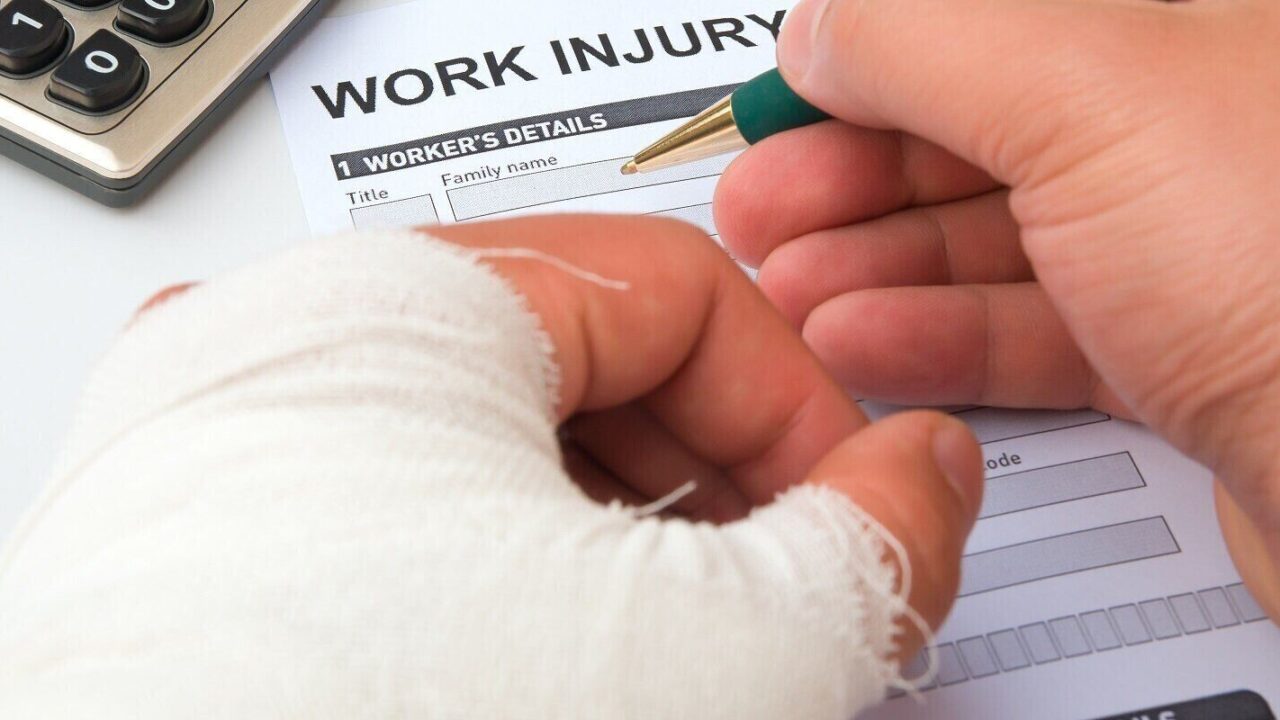filling up a work injury claim form with a wrapped hand