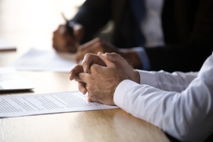 solicitor with clasped hands consulting client about document making financial legal deal