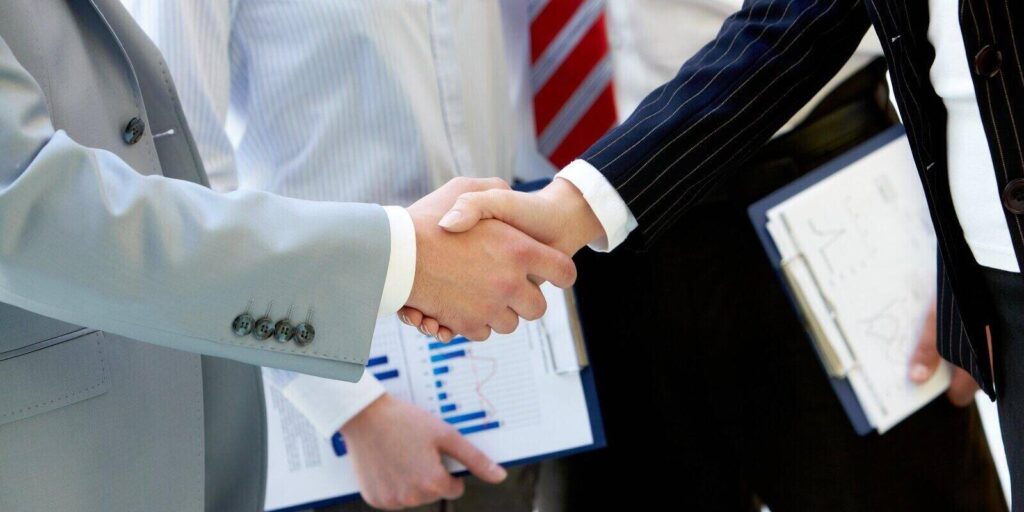 business partners handshaking after making agreement on background of two employees