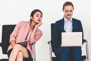 businesswoman looking at the screen of laptop computer of another businesswoman spying stealing idea