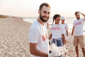 image of multinational eco volunteers cleaning beach from plastic at seashore