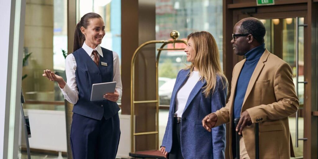 smiling manager in uniform using tablet pc while greeting the guests of the hotel