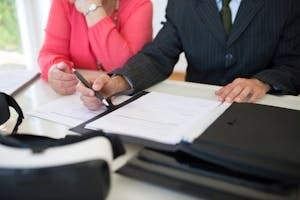 Trade Association Worker Holding Pen Over a Paper on Table