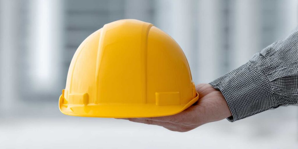 Government Contractor Hand Holding A Yellow Hard Hat