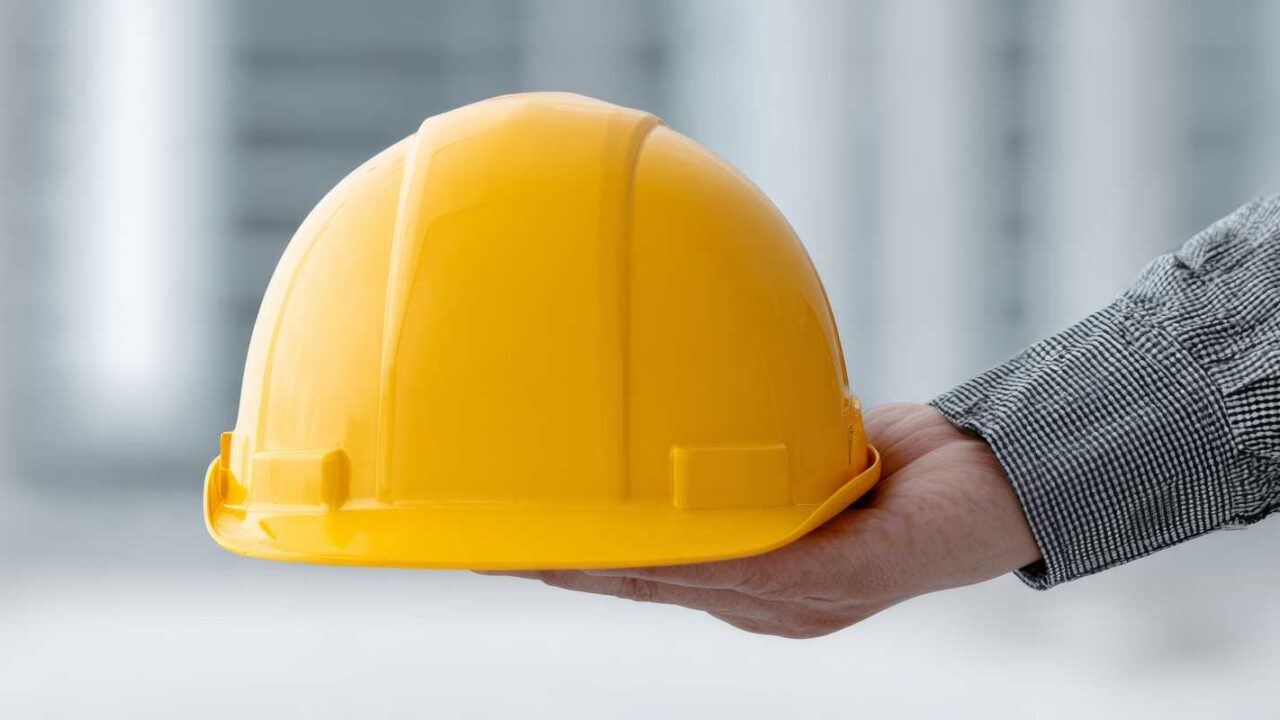 Government Contractor Hand Holding A Yellow Hard Hat