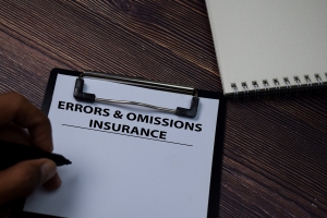 Person Writing E & O Insurance Gaps on White Paper