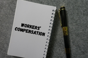 Workers’ Compensation Text on Notebook Near A Pen