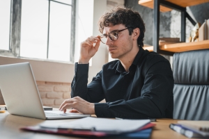 Businessman Reviewing Insurance Policy on Laptop and Worried About Mistakes in It
