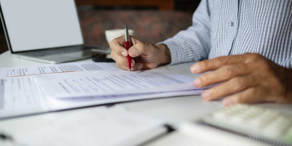 Businessman Eeading E&O Insurance Documents on His Desk